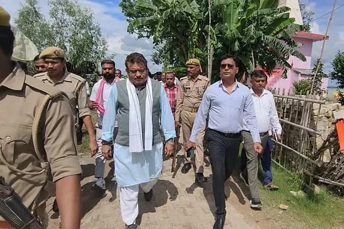 भ्रमण के दौरान गाँव की गली में अधिकारियों और पुलिसकर्मियों के साथ पैदल चलते हुए
