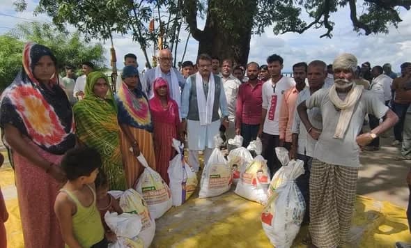 Villagers standing beside sacks of relief supplies during the distribution of relief kits