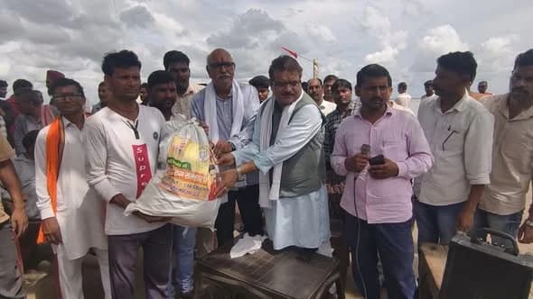 A relief kit being handed over to a villager while a crowd of residents stands around